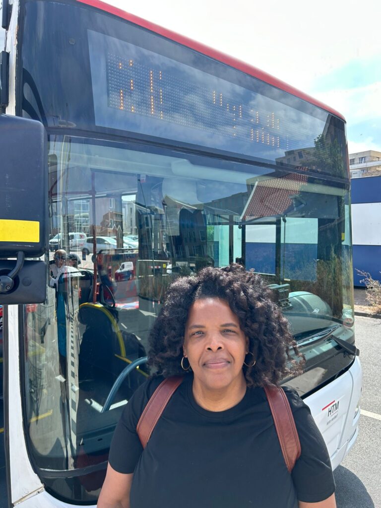 A woman standing in front of a bus.