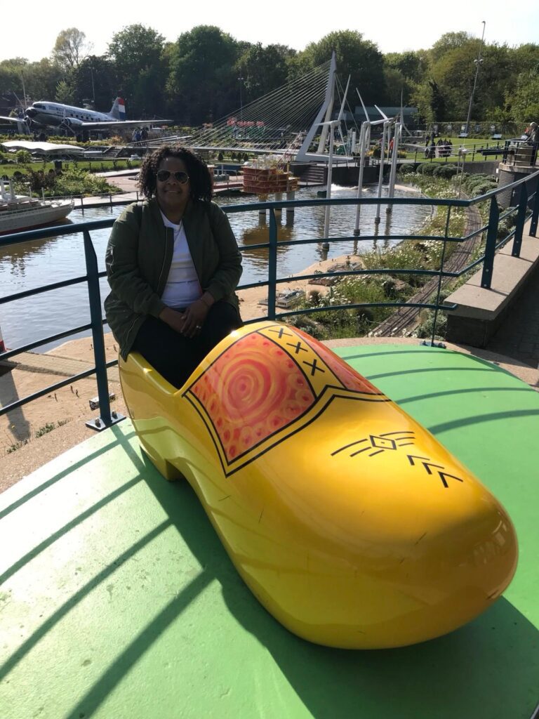 A woman sitting on top of a yellow shoe.