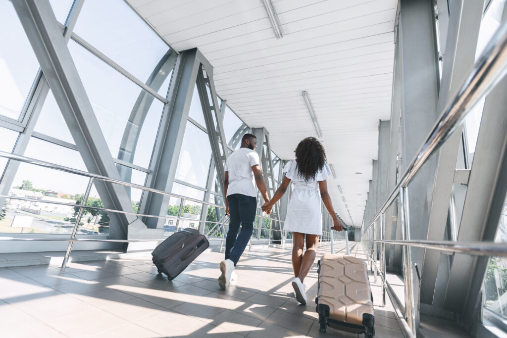 A man and woman walking down the stairs with luggage.