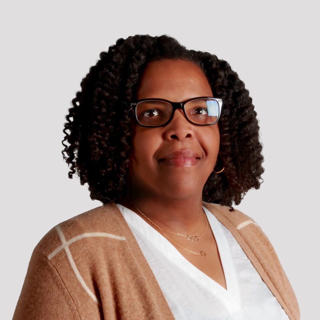 A woman with glasses and a brown jacket