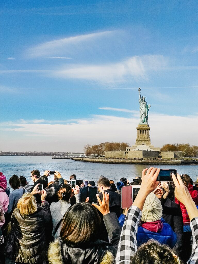 A crowd of people standing on the side of a body of water.