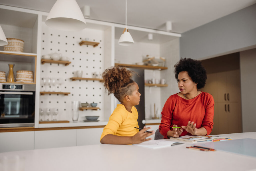 A woman and child sitting at the counter of a kitchen.