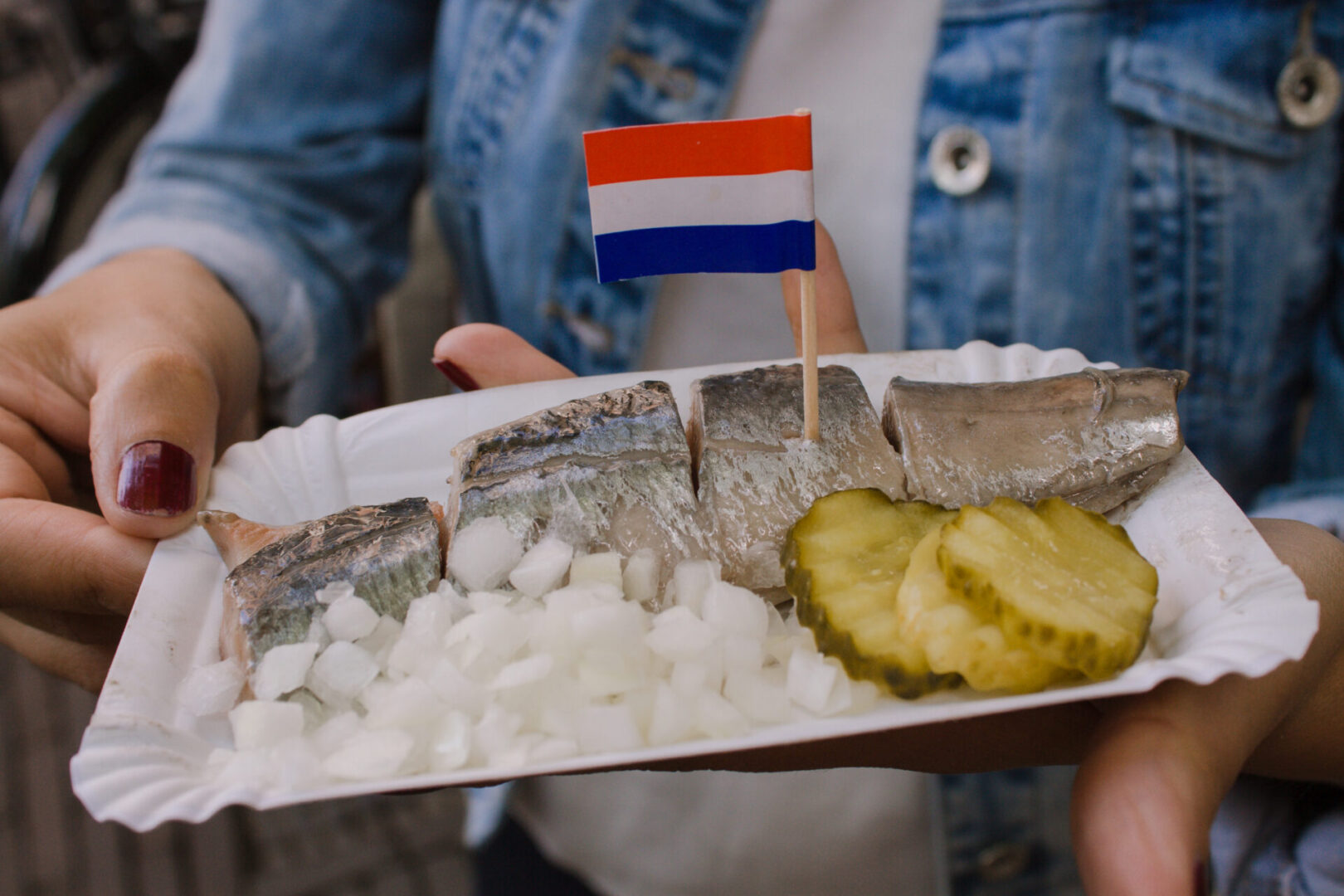The traditional dutch herrings with Netherlands flag, green pickles, and onions