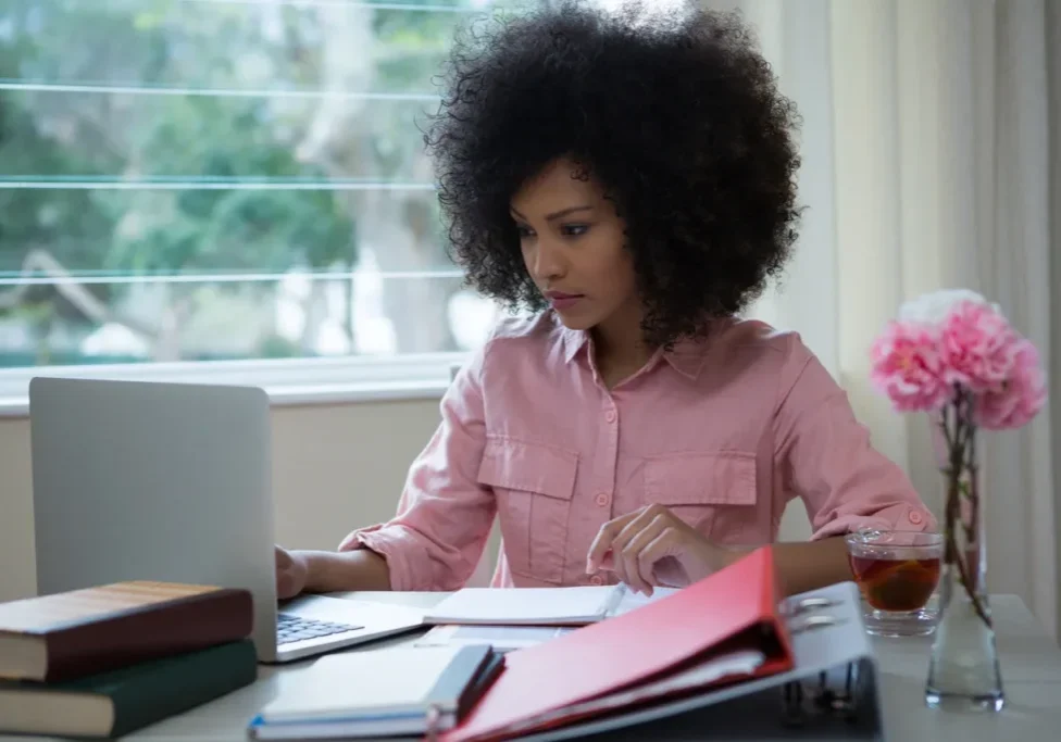 A woman sitting at her desk working on a laptop.