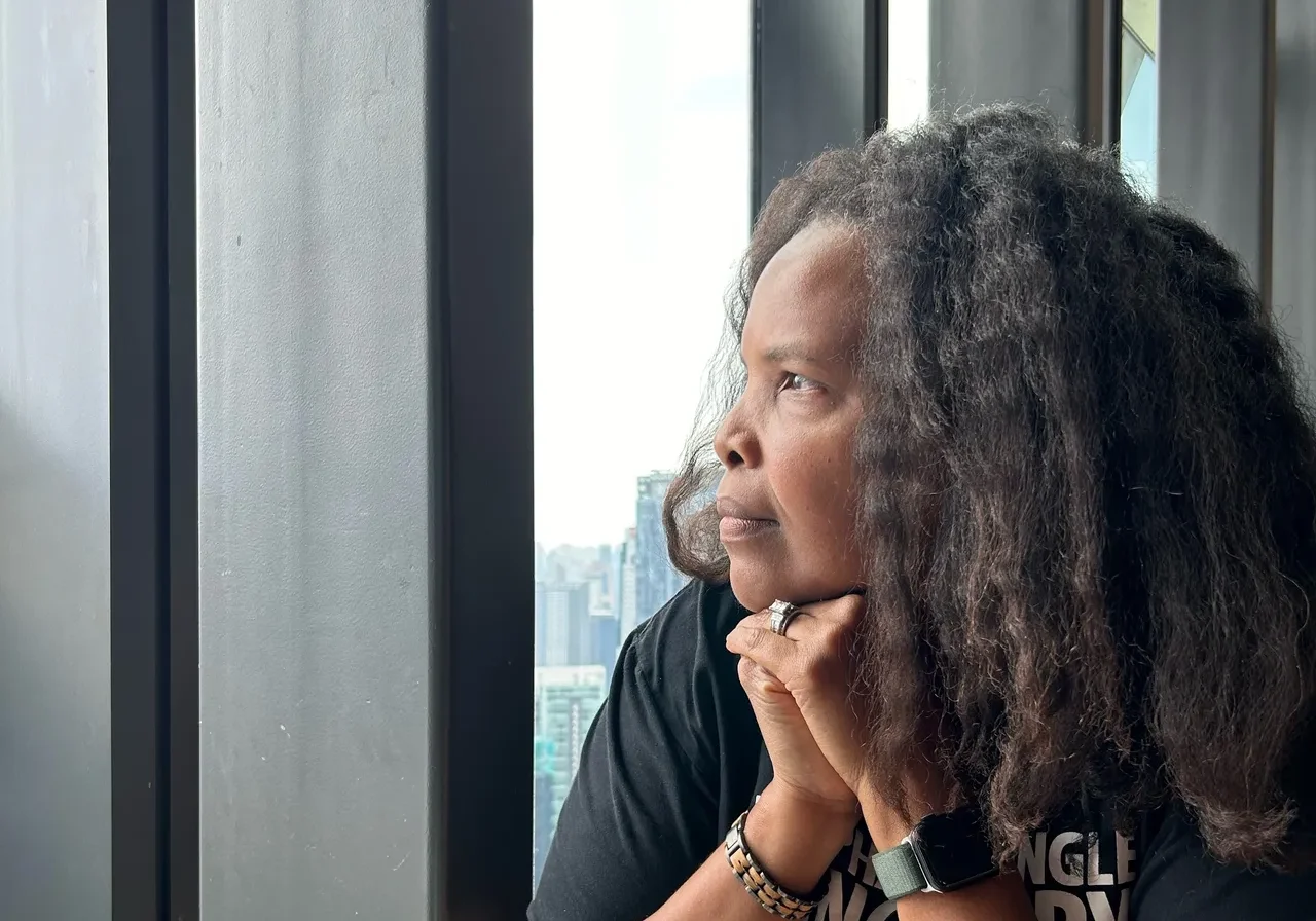 A woman with long hair is looking out of the window.