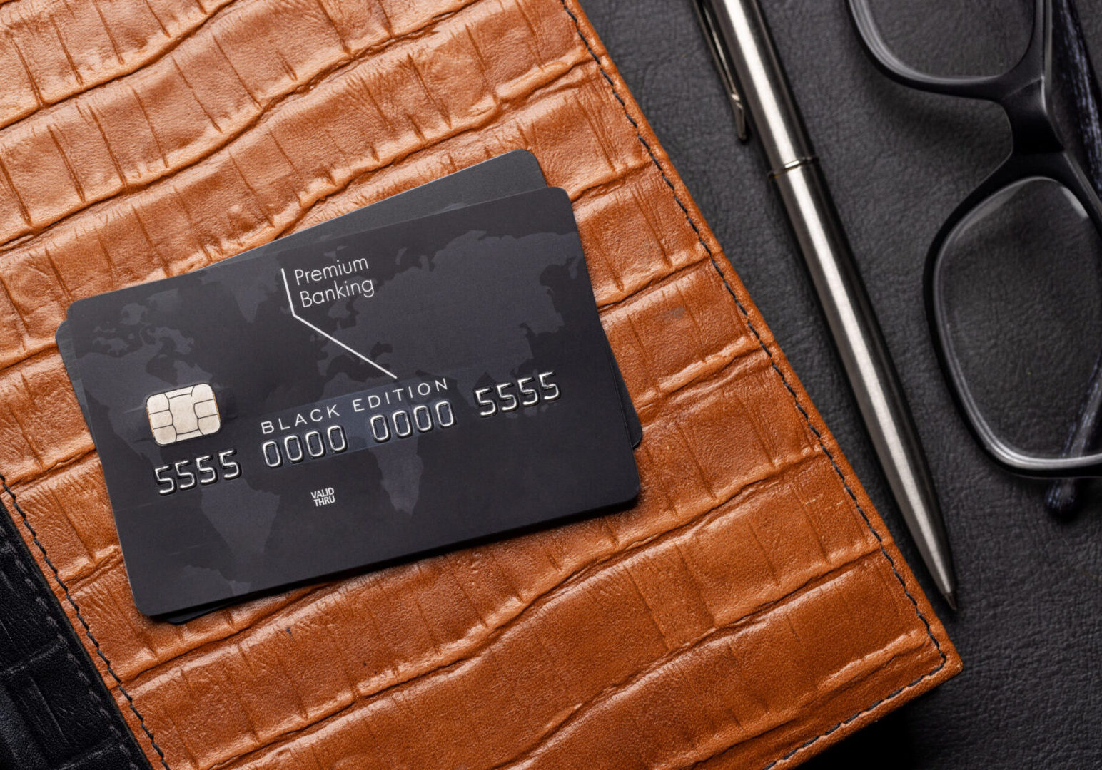 Black credit card on brown leather wallet.